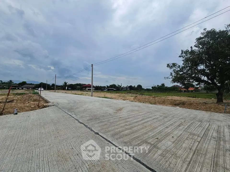 Expansive land plot with paved road and scenic views, ideal for development opportunities.