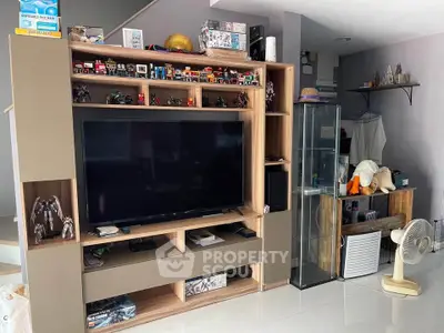 Modern living room with large TV and stylish shelving unit displaying collectibles.