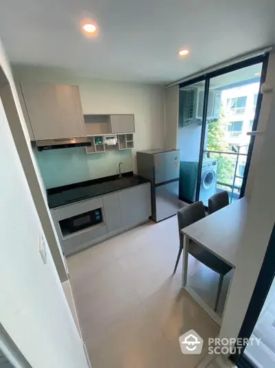 Modern kitchen with sleek cabinetry and high-end appliances, featuring an open layout that merges seamlessly with the living area, illuminated by natural light from the large window.