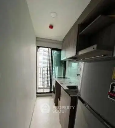 Compact kitchen with modern appliances and balcony view in urban apartment.