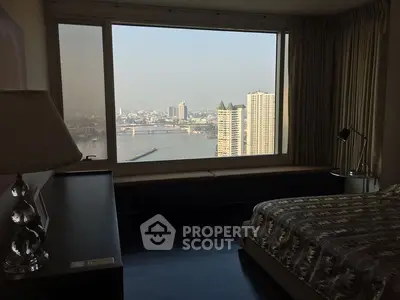 Luxurious bedroom with stunning river view and large window, perfect for relaxation and cityscape enjoyment.