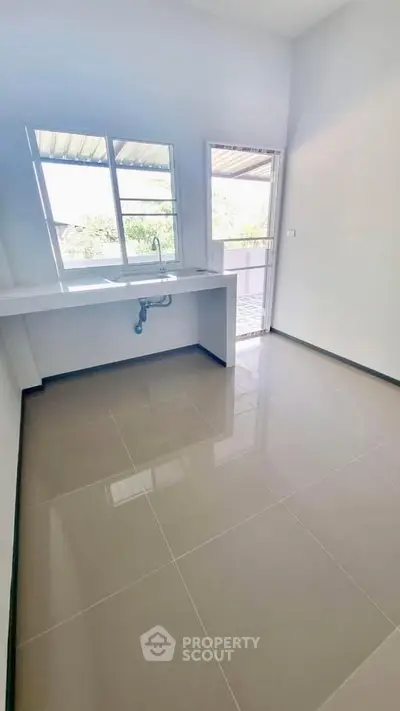 Bright kitchen space with large windows and balcony access, ideal for modern living.