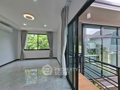 Spacious modern living room with large windows and balcony access, offering abundant natural light and serene views.