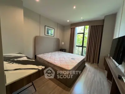 Spacious bedroom with large window and modern furnishings in a serene setting.