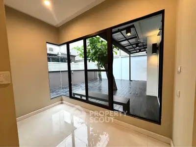 Modern interior with large windows overlooking a stylish patio with tree feature, perfect for natural light lovers.