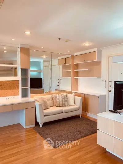 Modern living room with wooden flooring and built-in shelves, featuring a cozy sofa and stylish decor.