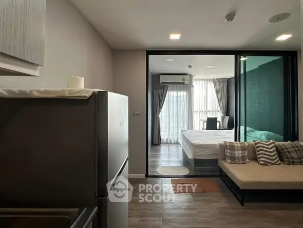 Modern apartment interior with open layout, featuring a cozy living area and a stylish bedroom with large windows.