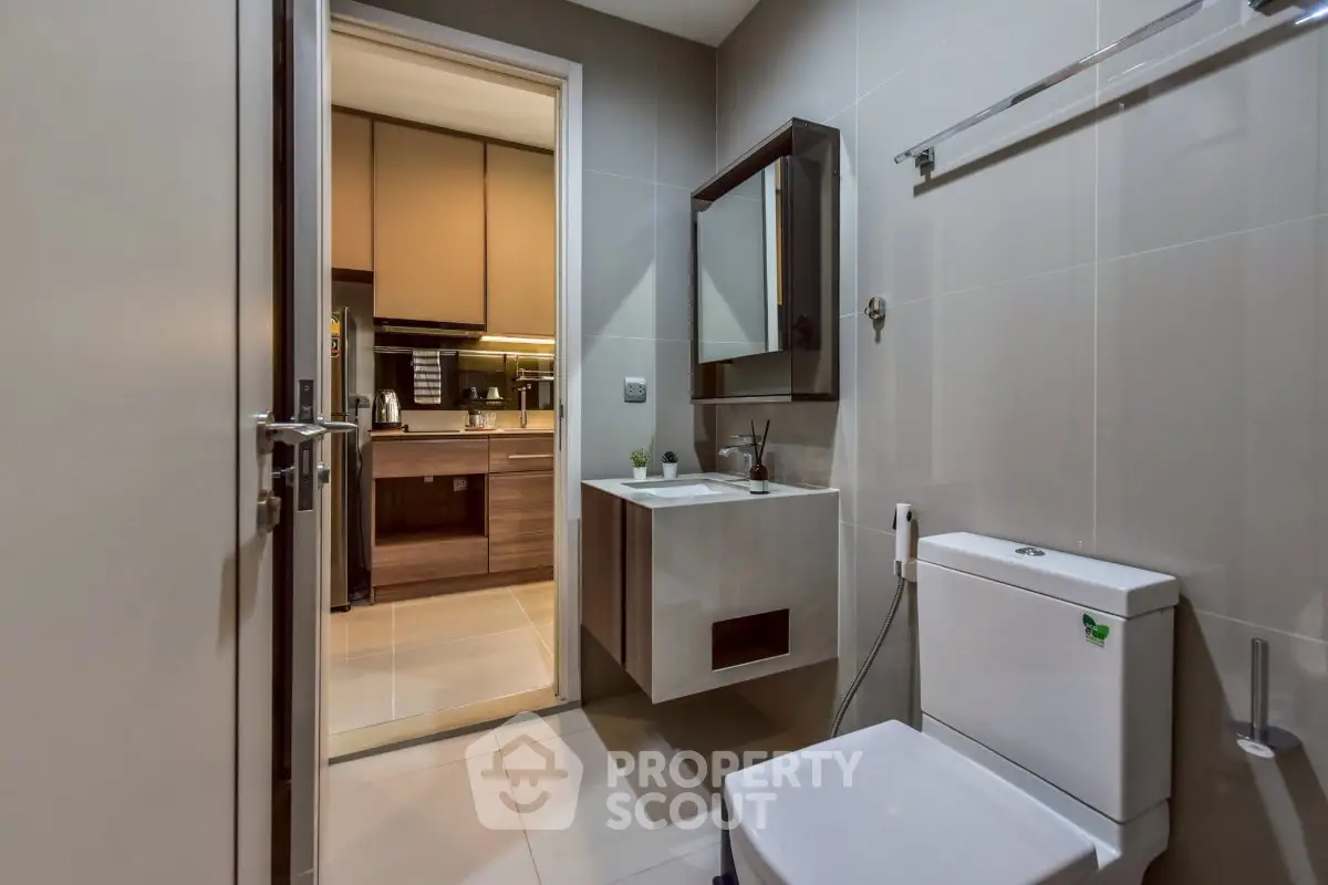 Modern bathroom with sleek fixtures and view into contemporary kitchen