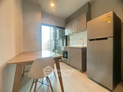 Modern kitchen with sleek appliances and dining area in bright apartment