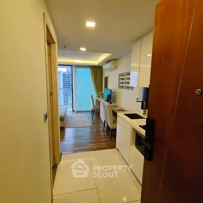 Modern apartment entrance with open kitchen and living area leading to a balcony with city view.