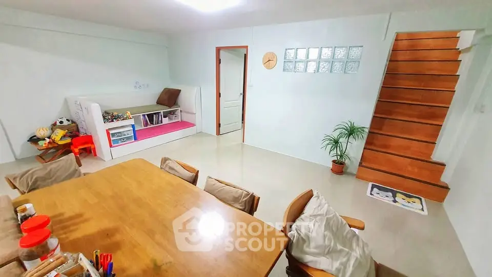 Spacious family room with wooden staircase and cozy dining area