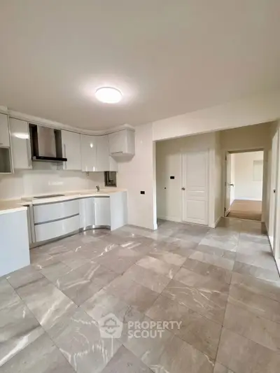 Spacious modern kitchen with sleek cabinetry and tiled flooring in a bright open layout.