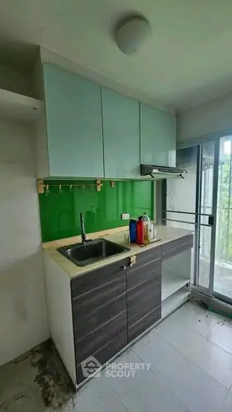 Modern compact kitchen with green backsplash and balcony access
