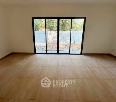 Spacious room with large sliding glass doors opening to a serene outdoor view.