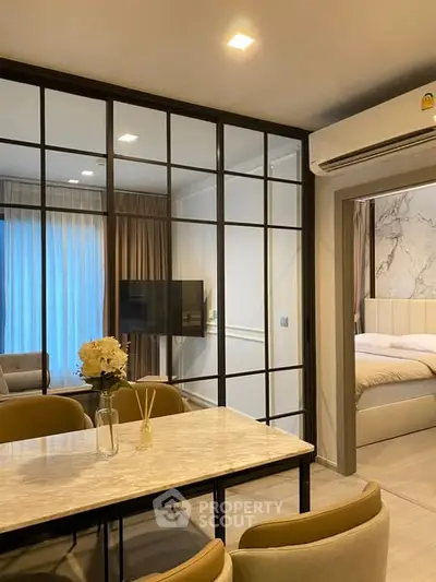 Modern open-plan living and dining area with glass partition and elegant decor.