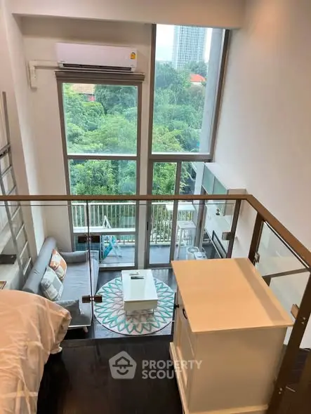 Modern loft apartment with large windows and lush green view, featuring stylish interior design and cozy living space.