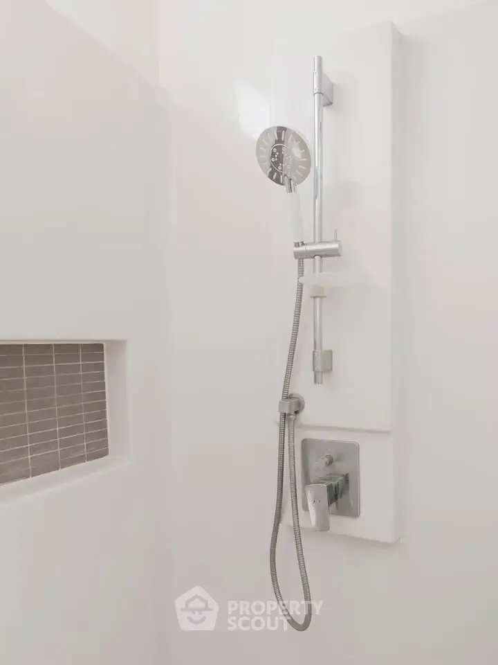 Modern bathroom shower with sleek fixtures and built-in shelf, perfect for contemporary living.