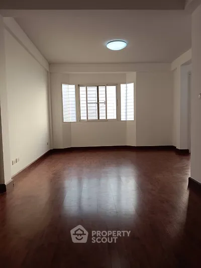 Spacious empty living room with wooden flooring and large window
