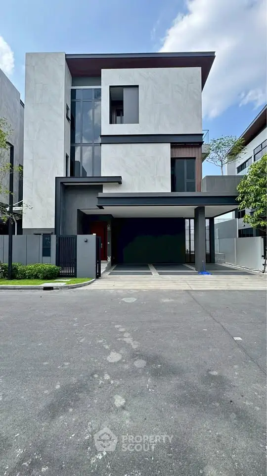 Modern luxury three-story house with sleek design and spacious driveway in upscale neighborhood.