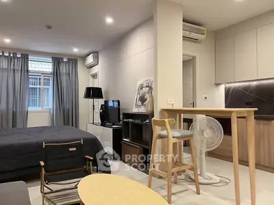 Modern studio apartment with open layout, featuring cozy living area and sleek kitchen design.