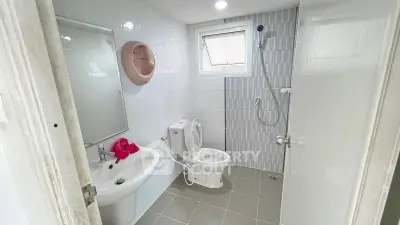 Modern bathroom with sleek fixtures and a minimalist design, featuring a shower and toilet in a bright, tiled space.