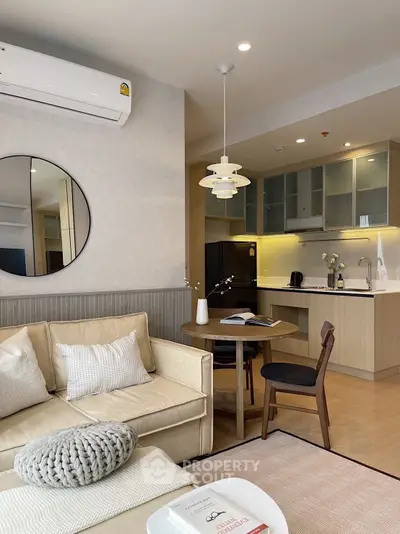 Modern living room with open kitchen, featuring stylish furniture and contemporary lighting.