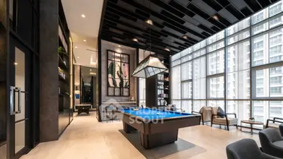 Luxurious modern living room with pool table and floor-to-ceiling windows in high-rise building.