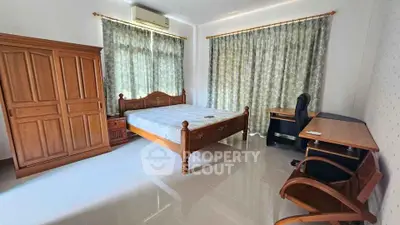 Spacious bedroom with wooden furniture and large windows for natural light