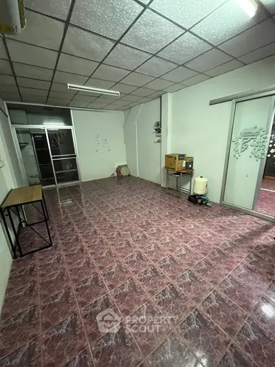 Spacious room with tiled flooring and sliding glass doors, ideal for versatile use.