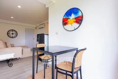 Modern living room with stylish decor and compact dining area in a bright apartment.