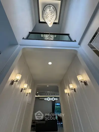 Luxurious high-ceiling living room with elegant chandelier and modern lighting fixtures.