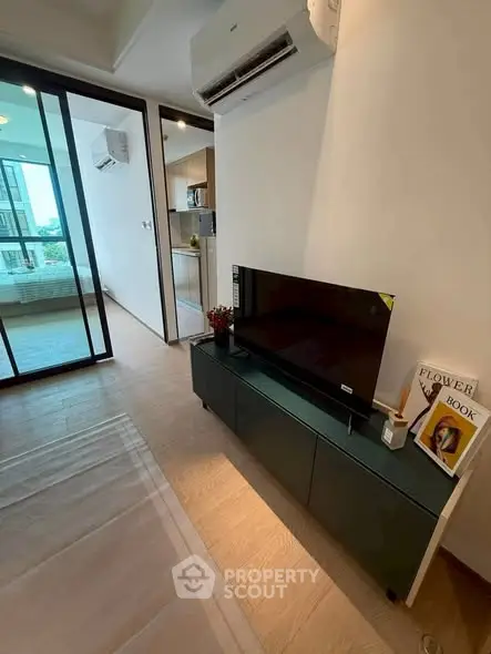 Modern living room with TV and air conditioning, featuring a sleek design and natural light.