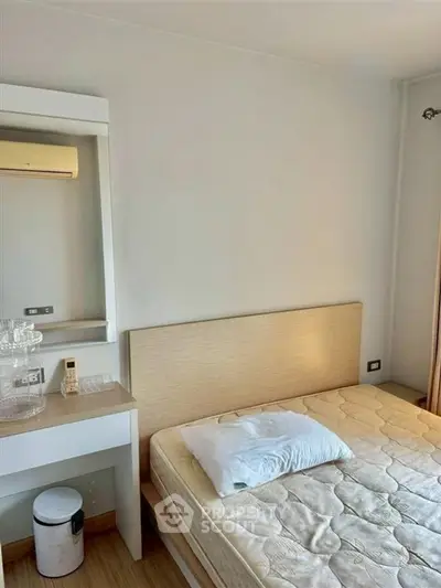 Cozy bedroom with minimalist decor and natural light, featuring a comfortable bed and air conditioning.