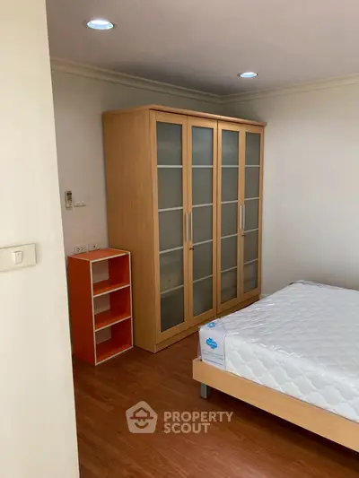 Cozy bedroom with wooden flooring and modern wardrobe, ideal for comfortable living.