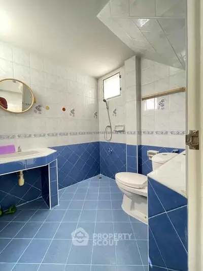 Spacious blue-tiled bathroom with modern fixtures and natural light.