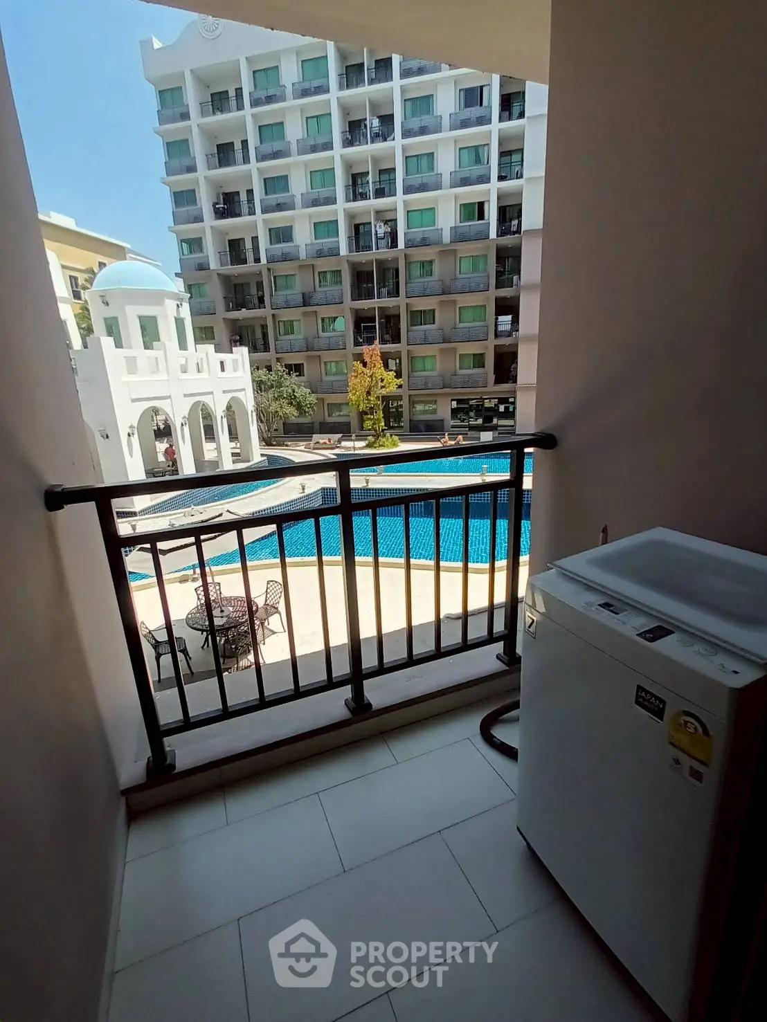 Charming balcony view overlooking a pool in a modern apartment complex.