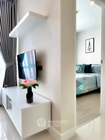 Modern living room with sleek TV setup and glimpse into stylish bedroom