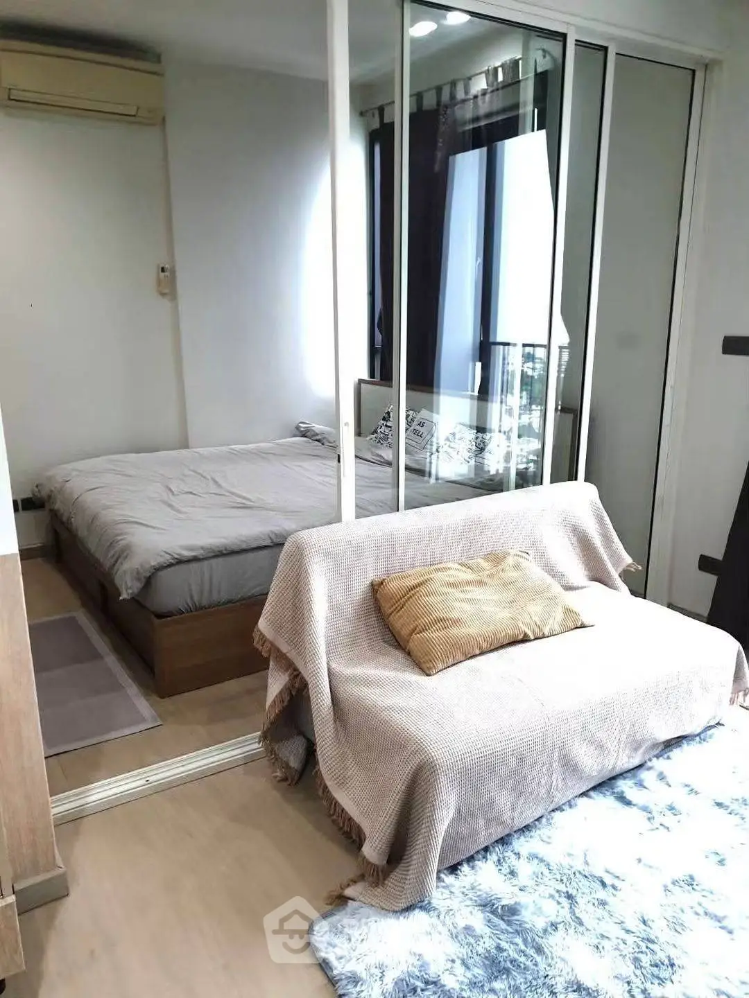 Cozy bedroom with mirrored closet and small sofa, perfect for urban living.