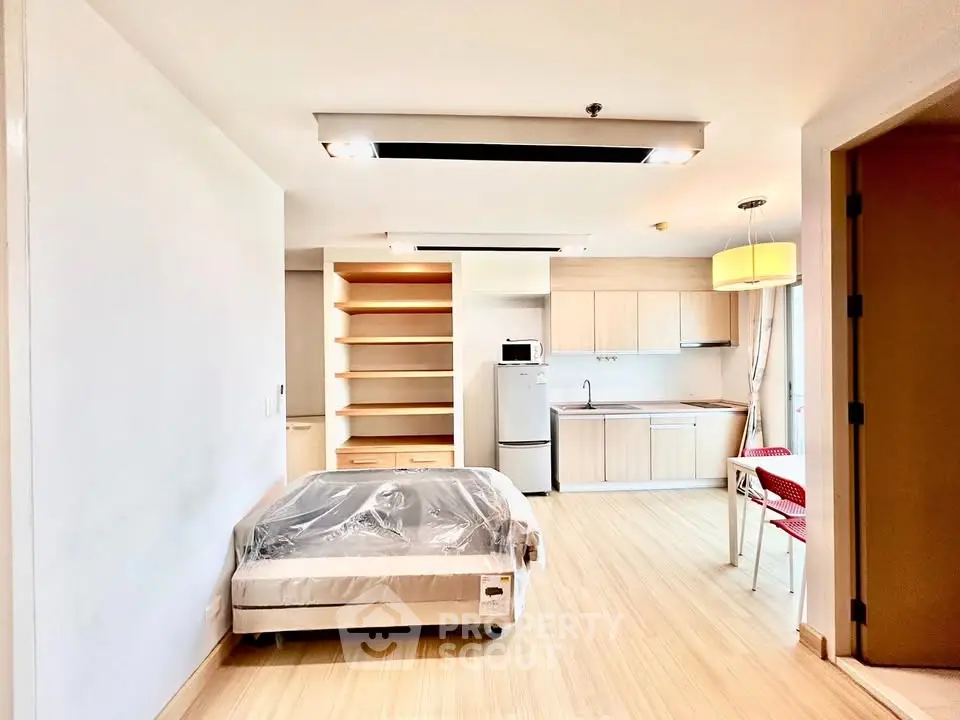 Modern studio apartment with open kitchen and cozy living space, featuring sleek wooden flooring and ample natural light.