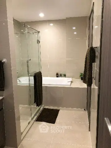Modern bathroom with glass shower and bathtub in elegant apartment