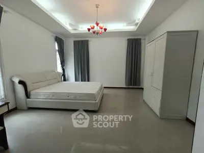 Spacious bedroom with elegant chandelier and large windows for natural light.