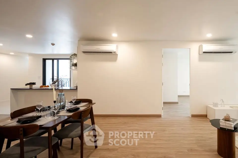 Spacious modern living room with dining area and open kitchen, featuring elegant wooden flooring and stylish decor.