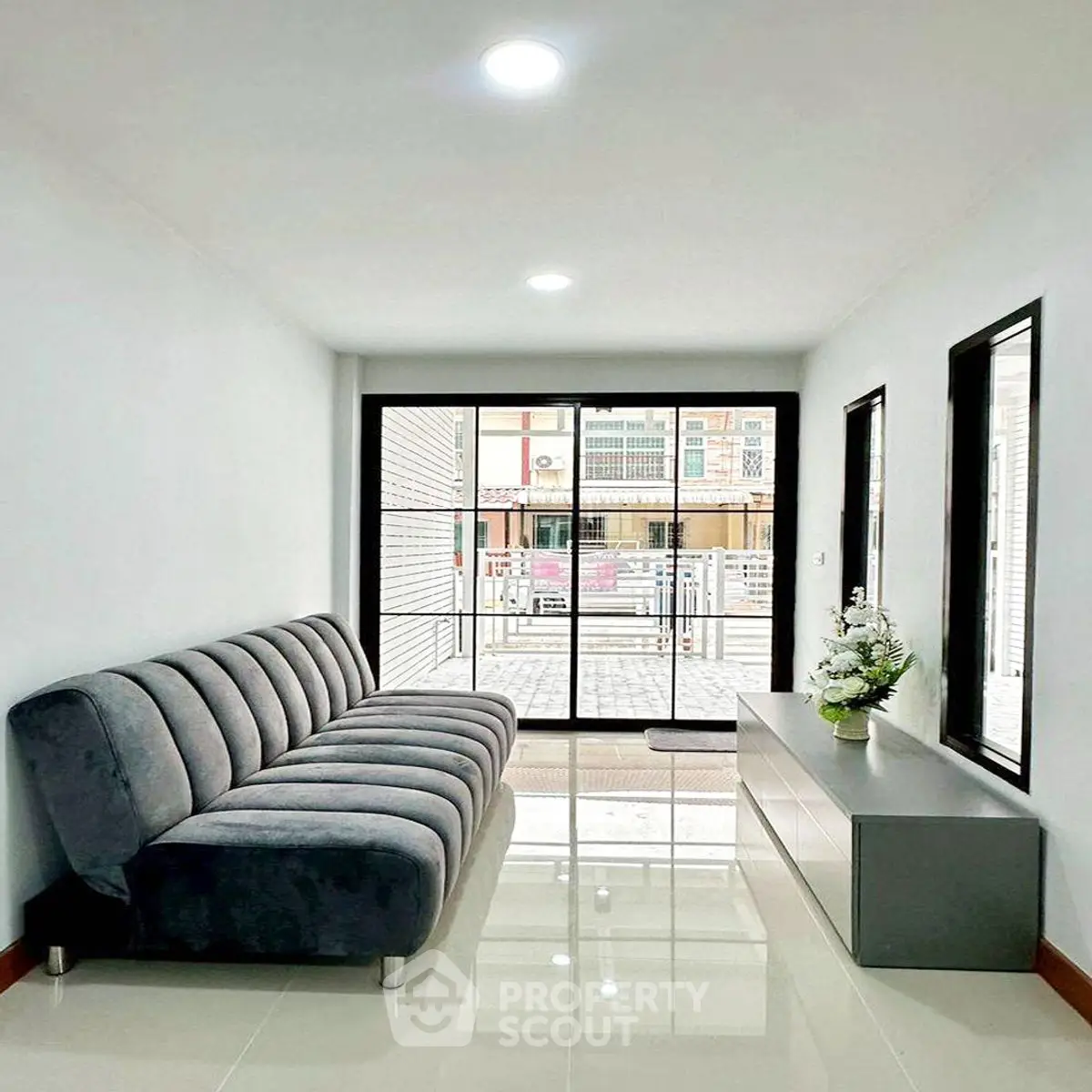 Modern living room with sleek sofa and large windows offering natural light.