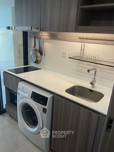 Modern kitchen with sleek cabinetry, washing machine, and induction cooktop in a compact layout.