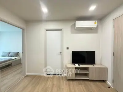 Modern living room with sleek design, featuring a wall-mounted air conditioner and flat-screen TV on a wooden stand.