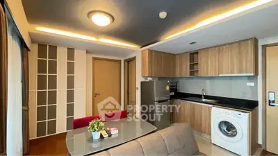 Modern kitchen with sleek cabinets, washing machine, and dining area in stylish apartment.