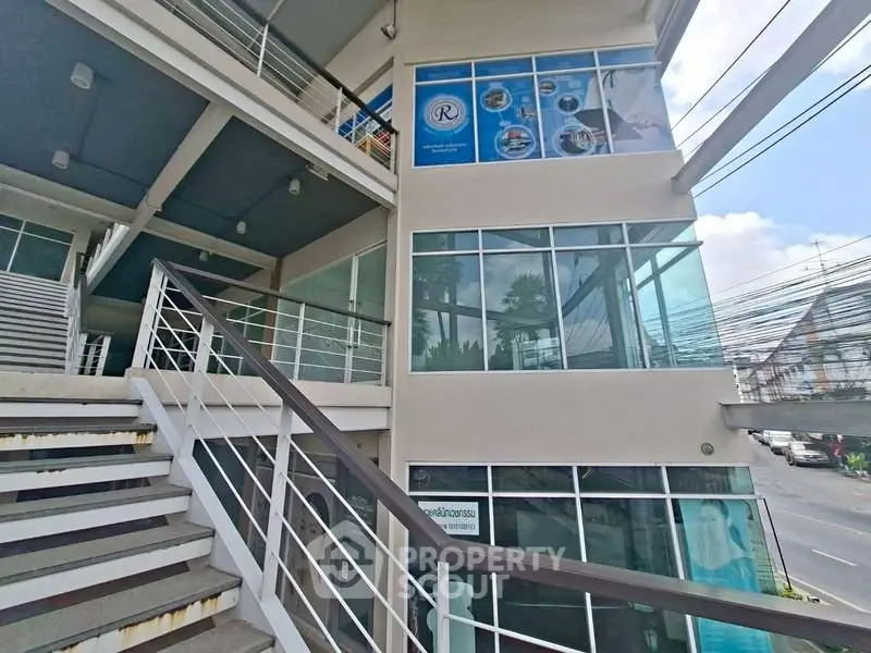 Modern commercial building exterior with glass facade and staircase, ideal for business opportunities.