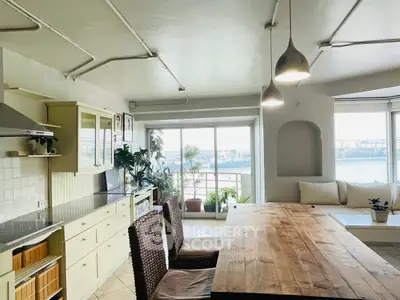 Spacious kitchen with open layout and stunning river view, featuring modern lighting and cozy seating area.