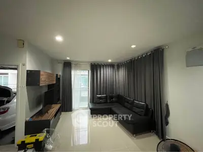 Modern living room with sleek black sofa and elegant curtains, featuring a stylish entertainment unit.