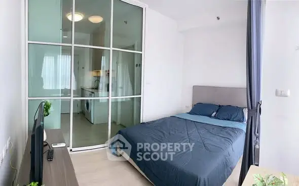 Modern bedroom with sliding glass doors and compact kitchen view, ideal for urban living.